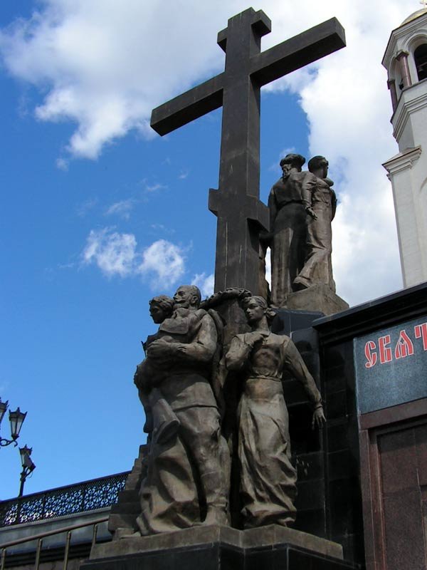 У входа в храм установлен Крест со скульптурными изображениями страстотерпцев